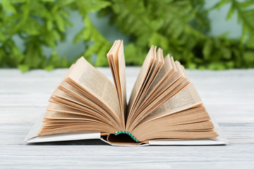 Open hardback book, on wooden table. natural background . Back to school. Copy space for text.