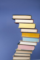 Open stacking book, hardback colorful books on wooden table and blue background. Back to school. Copy space for text. Education business concept.
