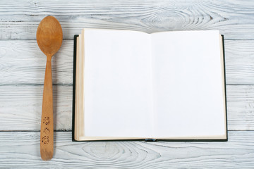 Recipe cook blank book on wooden background, spoon, rolling pin, checkered tablecloth