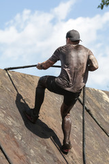 Mud race runners,participant for overcoming barriers through ropes  