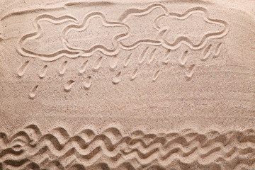 Clouds and waves drawn on beach sand