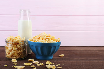 Cornflakes and bottle of milk on wooden table