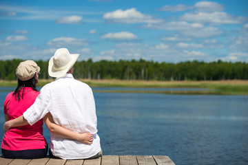 pair of lovers hugging, sitting on the shore of the lake