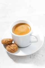 cup of espresso and almond cookies on a white table, vertical