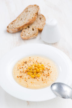 corn soup in plate and bread, top view, vertical