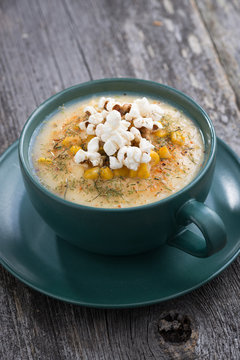 corn soup with popcorn in ceramic cup on wooden table, vertical, top view