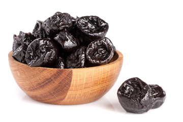 Dried plums or prunes in wooden bowl isolated on white background