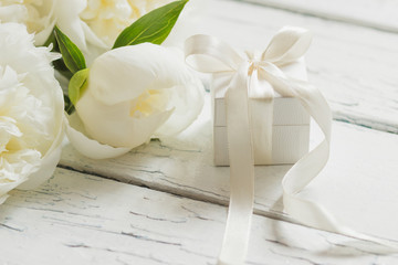 Bouquet of white peonies and present box on the wooden table