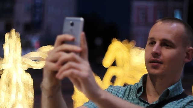 Man taking photo with camera phone at night. Young casual man taking picture with camera phone on the street.