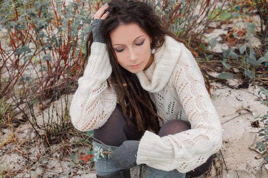 attractive young woman in white sweater outdoors