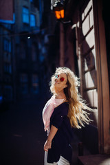 Fototapeta na wymiar Look from behind at blonde woman posing in blue shirt in the rays of sun