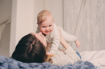 happy mother and baby playing at home in bedroom. Cozy family lifestyle in modern scandinavian interior.