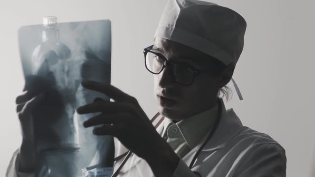 Drunk doctor makes a diagnosis. A medical worker drinks vodka.
