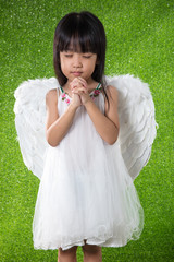 Asian Chinese little girl wearing angel wings and praying