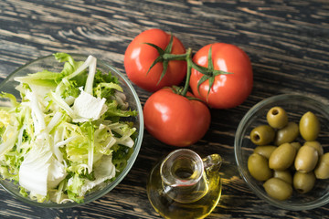 Salad leaves with olives, tomato and oil.