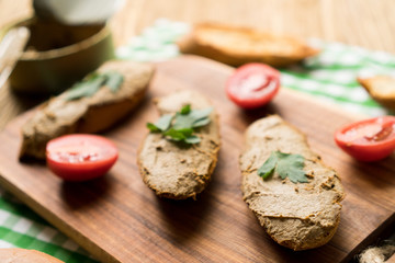 Liver pate on the bread on wooden tray.
