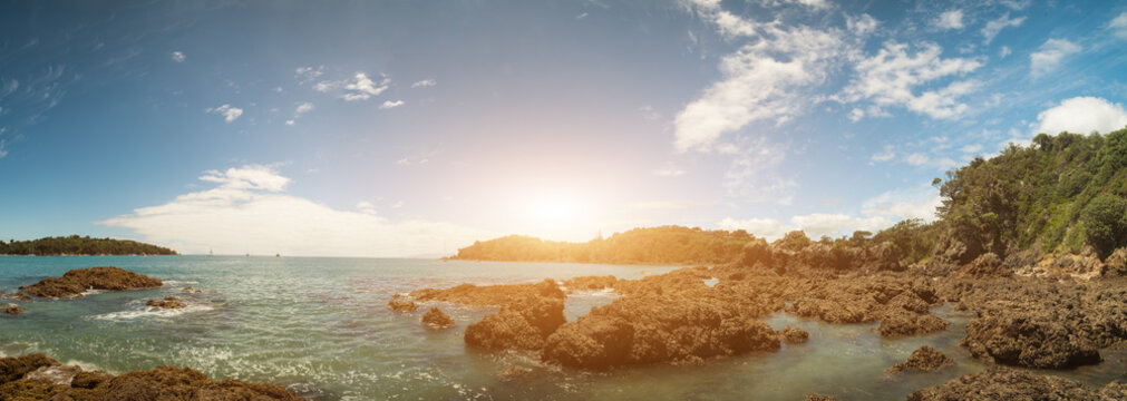 Panorama of a sandy beach with volcanic stones and turquoise sea in New Zealand
