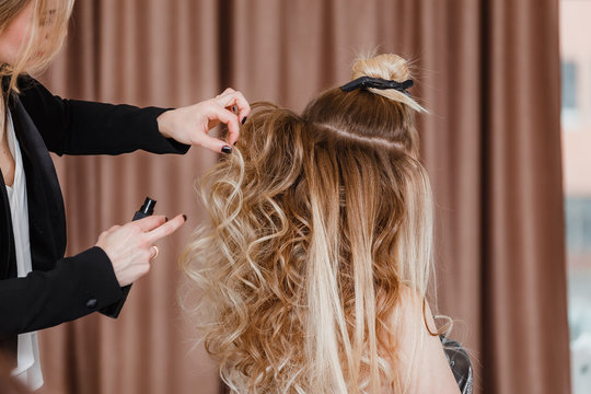 Golden haired blonde girl doing the volume Curling by hairdresser in the beauty salon