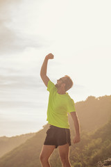 Fototapeta na wymiar Success of a man after jogging / exercising on a clif near the sea / ocean.
