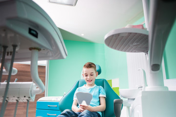 A small boy at a reception with a dentist, sits in a chair