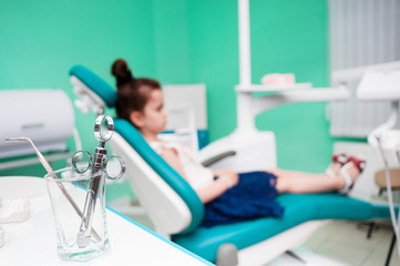 A little girl at a reception with a dentist, sits on a chair