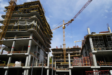 Construction crane and unfinished buildings with blue sky on background