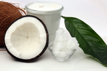 Coconut with leaves and coconut oil in jar on wooden background