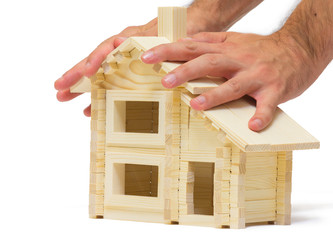 Hands saving small wooden toy house isolated on white background