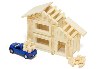 Toy wooden house with pickup truck isolated on white background