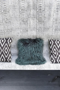 Black and white ethnic fabric covered bench with black and white geometric pattern cushions and dark green fur
