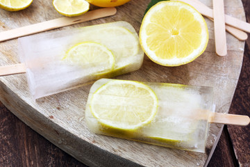 Healthy lemon popsicles with fresh lime slices on wooden background