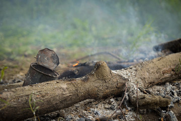 An old rusty can of food left by someone in a pile of ash or a burning fire