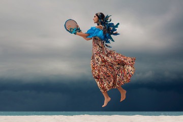 attractive young woman with tambourine outdoors. One minute before storm - obrazy, fototapety, plakaty
