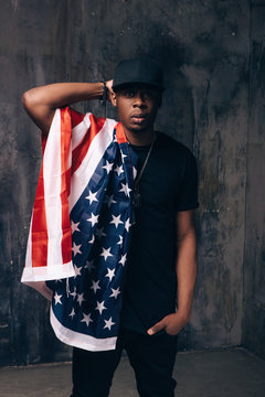 Confused afro american man with american flag on dark background. Patriot, immigration, independence day, social problem, usa citizen concept