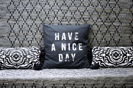 Sofa covered with an ethnic patterned fabric and black and white cushions "have a nice day"