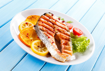 Grilled salmon with vegetables on blue wooden table