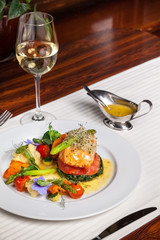 beautiful serving dishes in the restaurant, red fish salmon with vegetables on a white plate in a restaurant on a black background with white wine stokanom