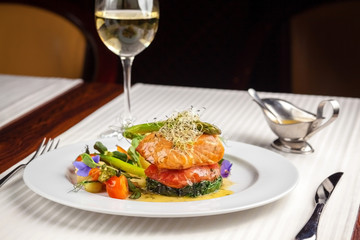 beautiful serving dishes in the restaurant, red fish salmon with vegetables on a white plate in a...