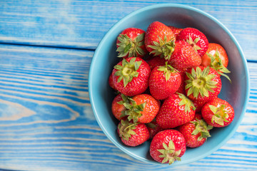 Ripe red strawberries in white bowl. Top view.