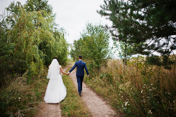 Bride and groom take walk in the countryside with stunning nature on their wedding day.