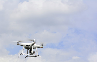 White drone quadrocopter hovers in the blue sky background with modern technology using take a photo and video shooting