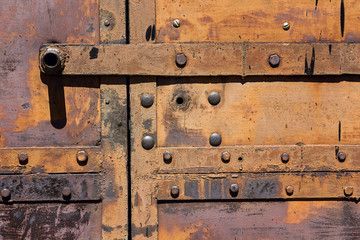 Fragment of old rusty iron gates with rivets.