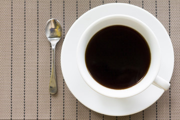 White coffee cup and spoon on the table top viwe with space.