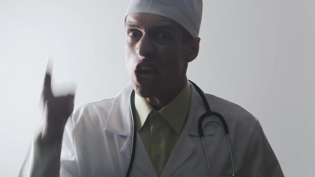 The aggressive doctor screams and waves. Threat of violence. Evil medical worker.