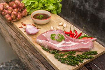 Raw pork on cutting board and vegetables Put on a wooden table.
