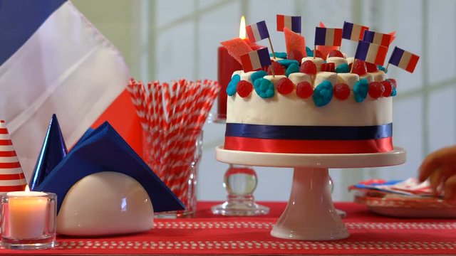 4k France Bastille Day celebration party table with showstopper cake decorated with candy, stars and flag, presenting cake and placing it on the table.