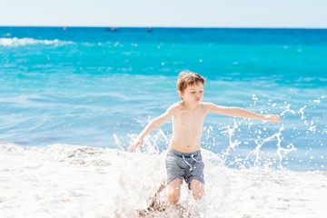 Fototapeta na wymiar Little boy playing at the beach. Happy summer vacations.