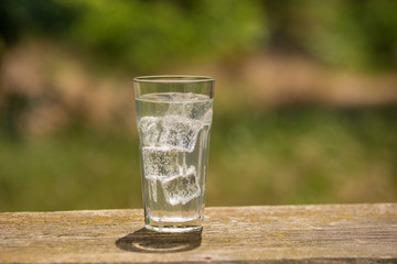 A glass of soda water on an old board, on the nature