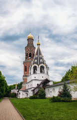Fototapeta na wymiar Ancient Orthodox Church with Golden domes and white stone bell tower in the monastery of the Ryazan region.