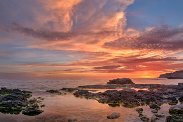 sea sunset on the rocky beach with unusually beautiful sky